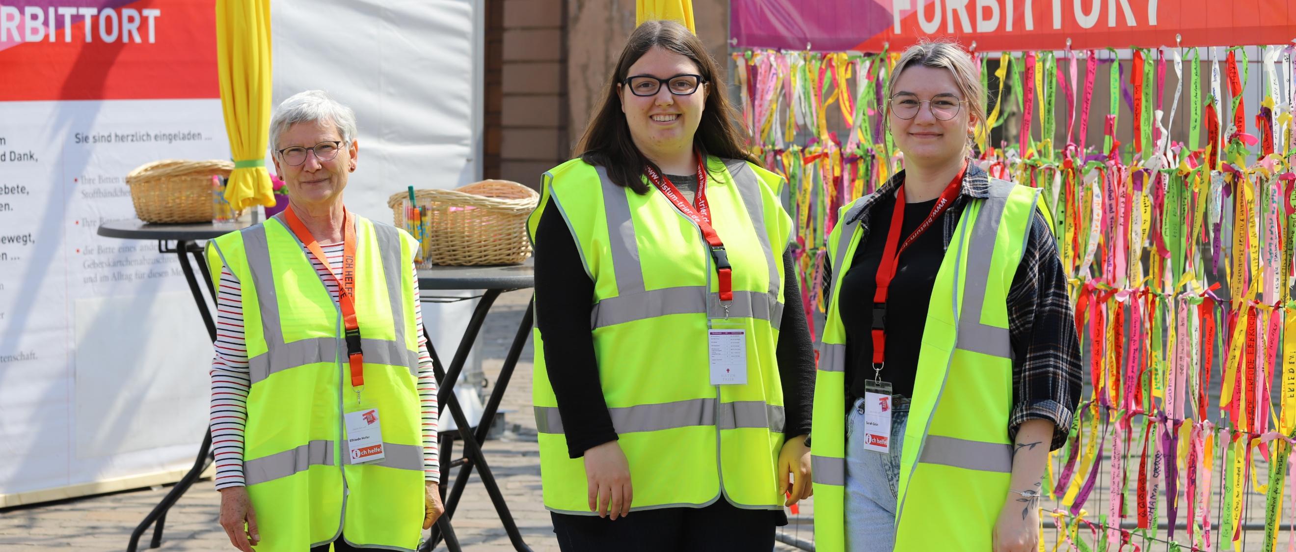 drei Frauen mit Warnwesten stehen vor dem Fürbittort der Heilig-Rock-Tage