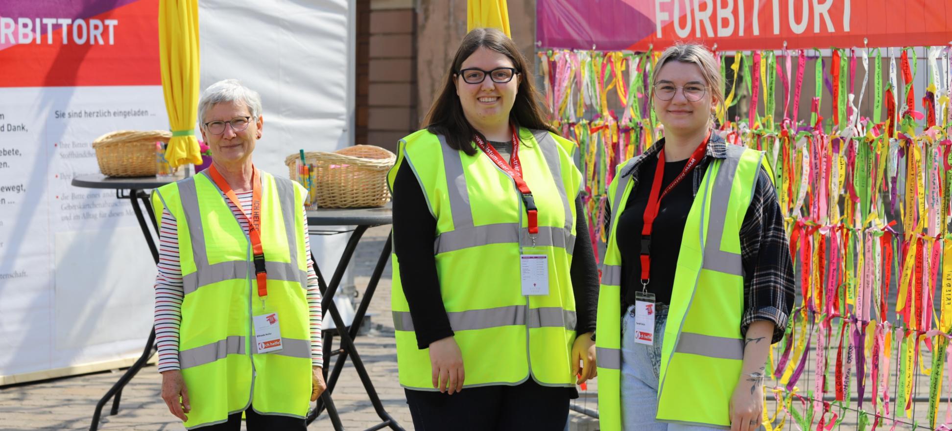 drei Frauen mit Warnwesten stehen vor dem Fürbittort der Heilig-Rock-Tage