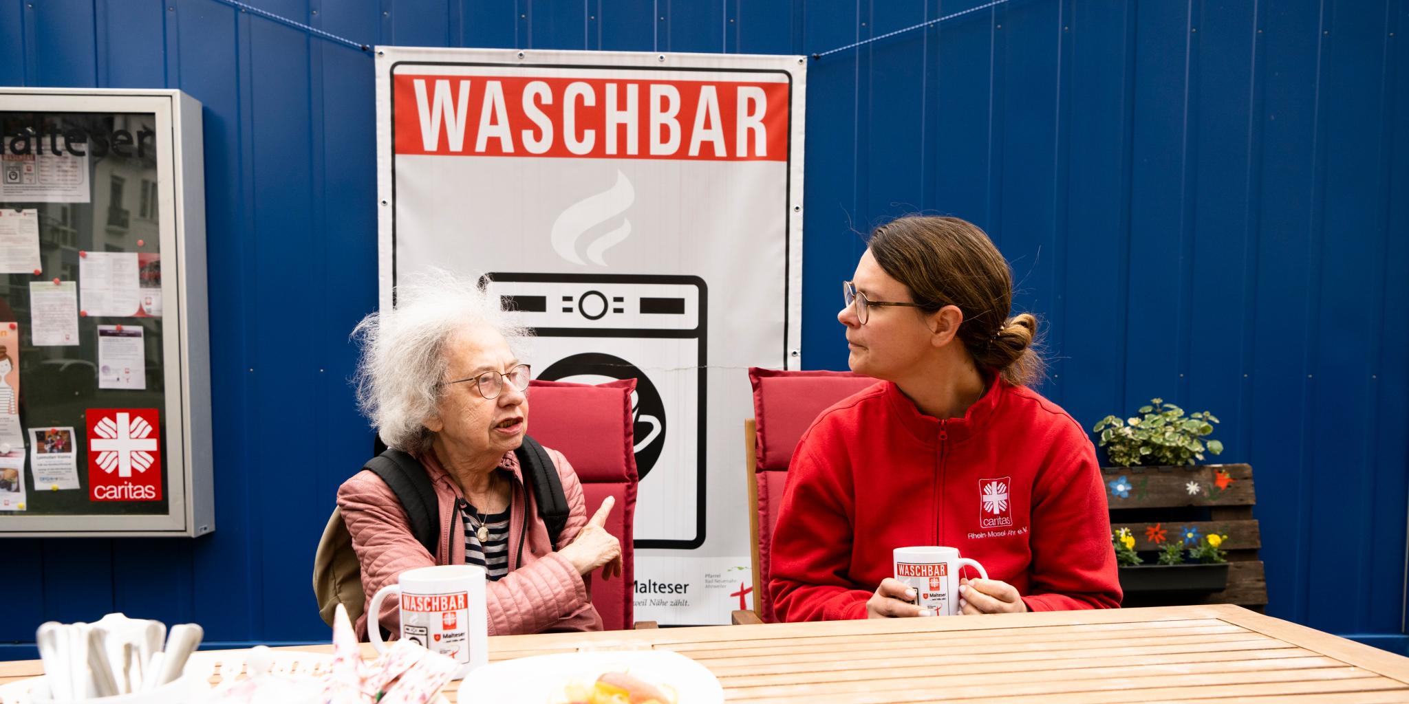 Eine Mitarbeiterin der Caritas hört einer Flut-Betroffenen in der Waschbar zu.