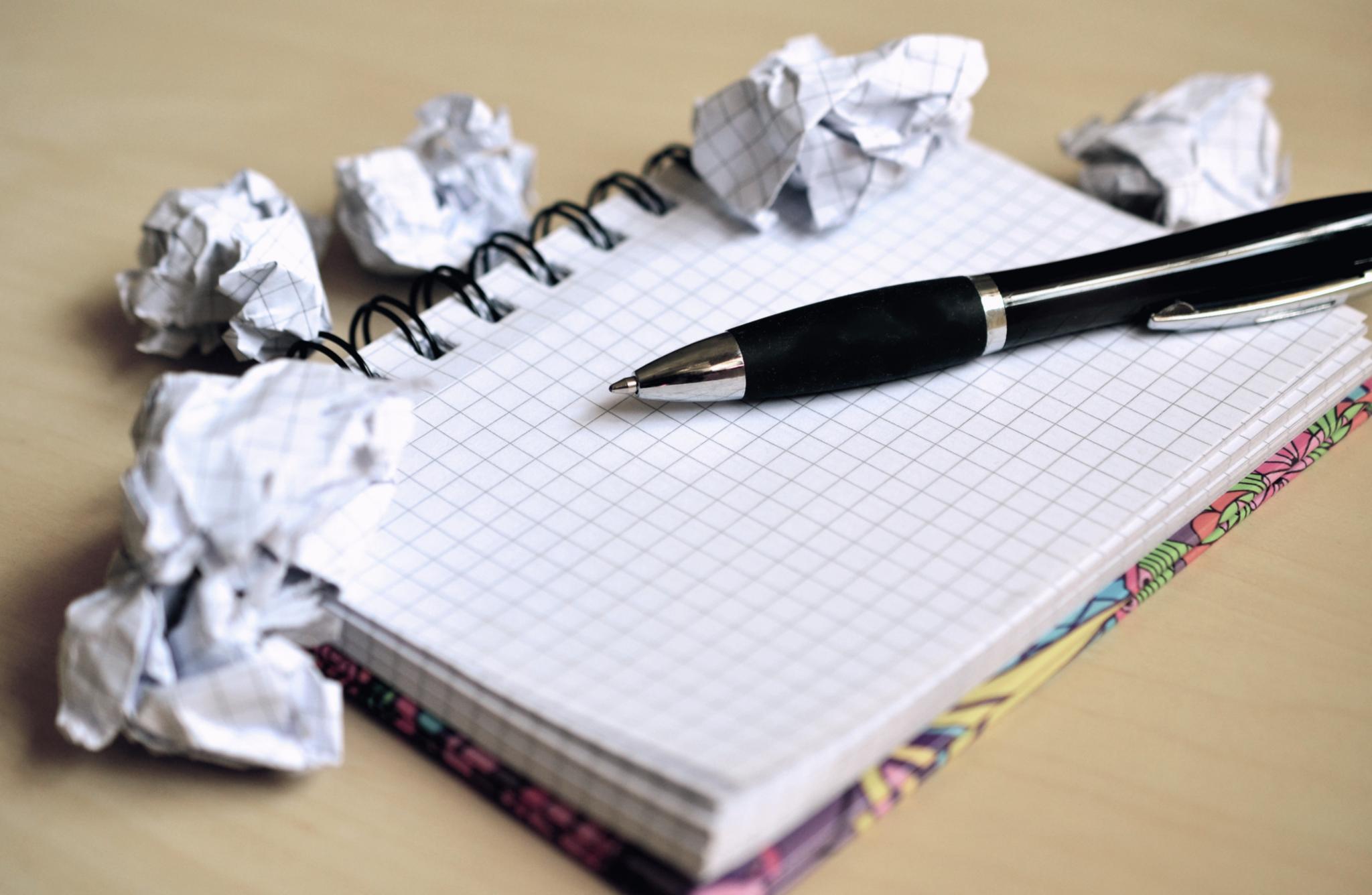 Schwarzer Stift auf kariertem Notizbuch, umgeben von zerknülltem Papier (c) congerdesign_pixabay_pfarrbriefservice Schwarzer Stift auf kariertem Notizbuch, umgeben von zerknülltem Papier
