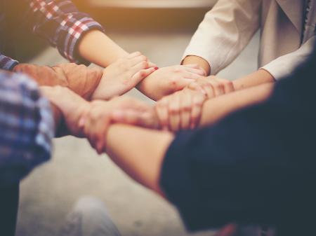 Menschen die sich an den Händen halten und mit ihren Händen einen Kreis bilden