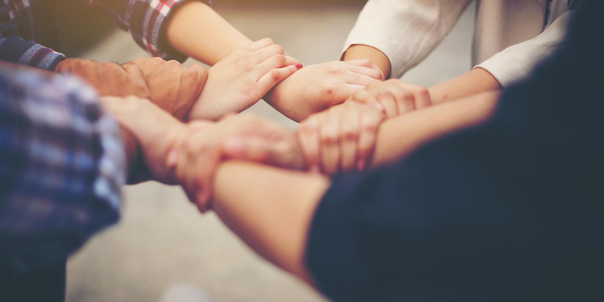 Menschen die sich an den Händen halten und mit ihren Händen einen Kreis bilden