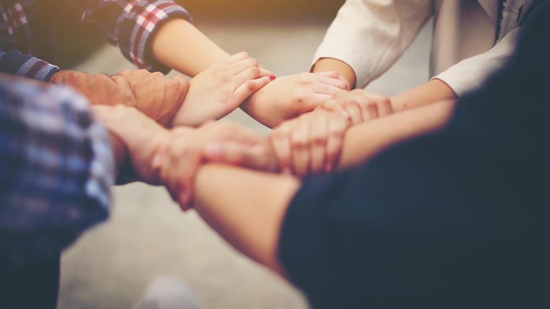 Menschen die sich an den Händen halten und mit ihren Händen einen Kreis bilden