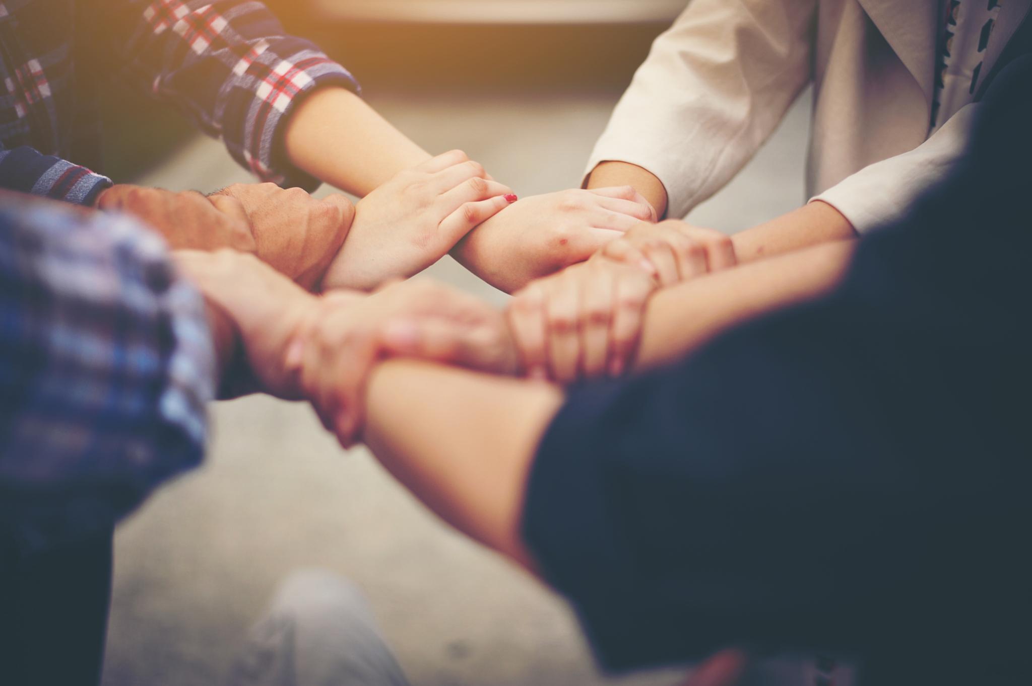 Menschen die sich an den Händen halten und mit ihren Händen einen Kreis bilden