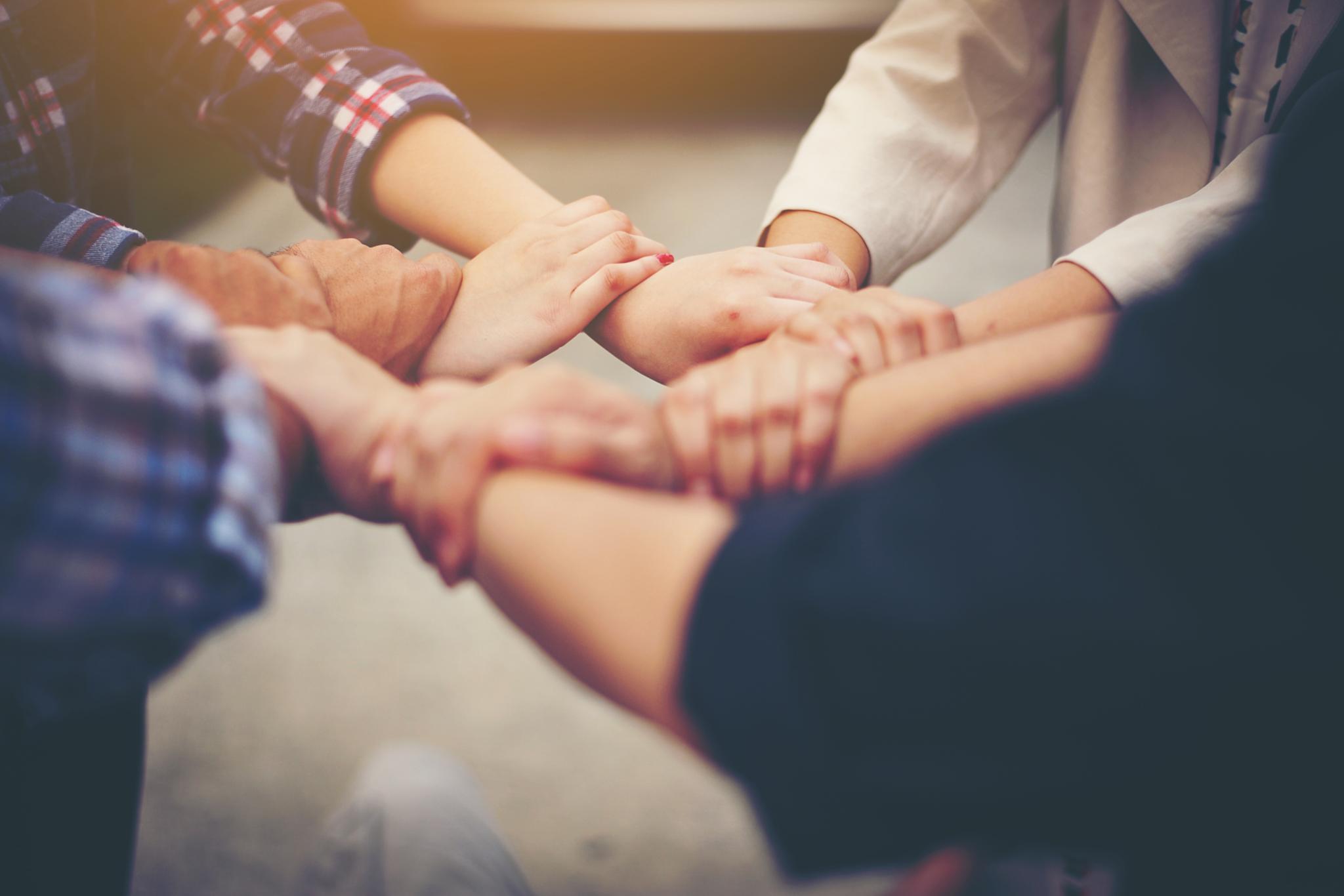 Menschen die sich an den Händen halten und mit ihren Händen einen Kreis bilden