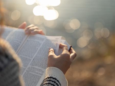 Frau mit Bibel in der Hand vor einem Gewässer
