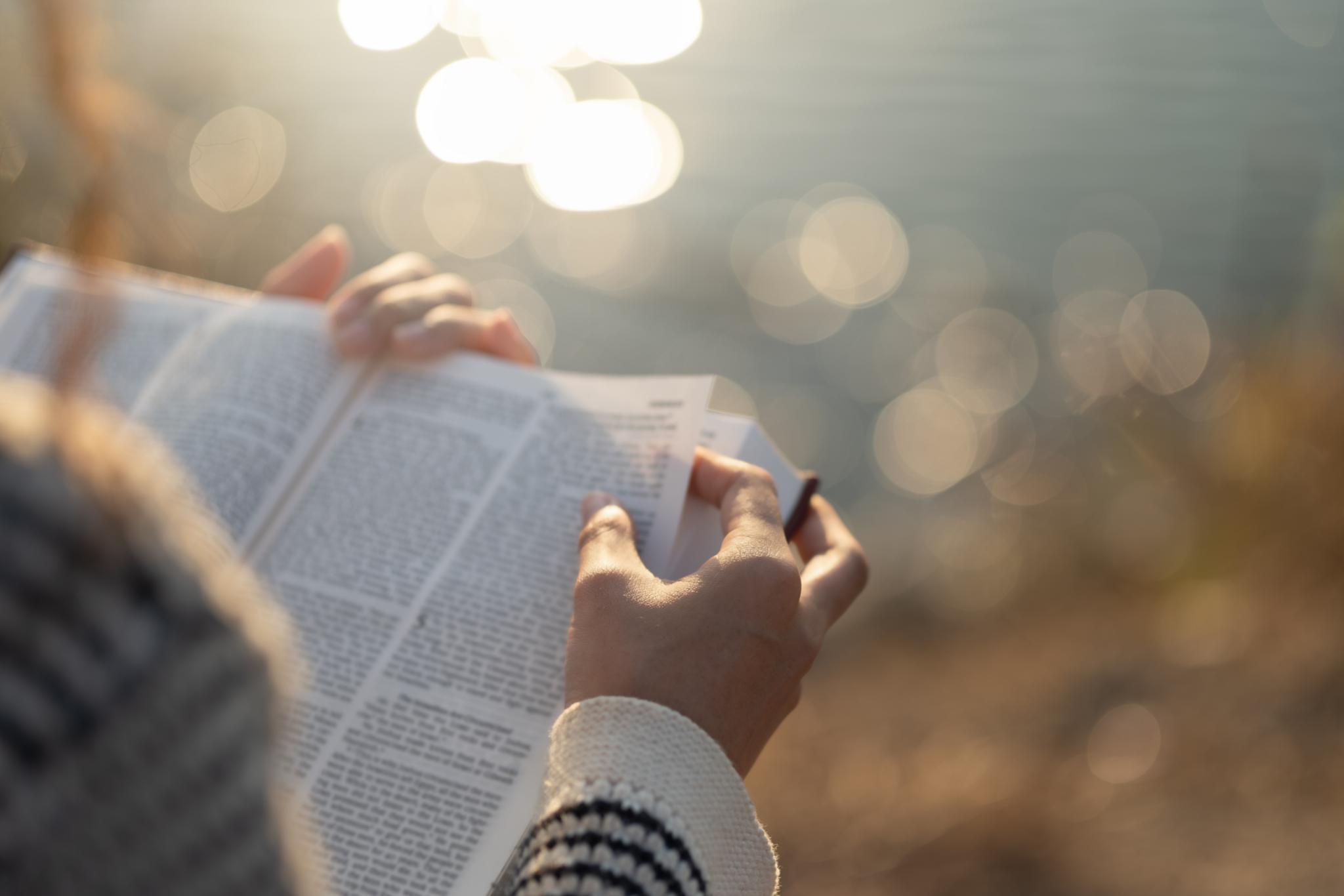 Frau mit Bibel in der Hand vor einem Gewässer
