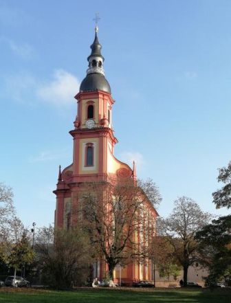 Kirche mit hohem Turm hinter Bäumen