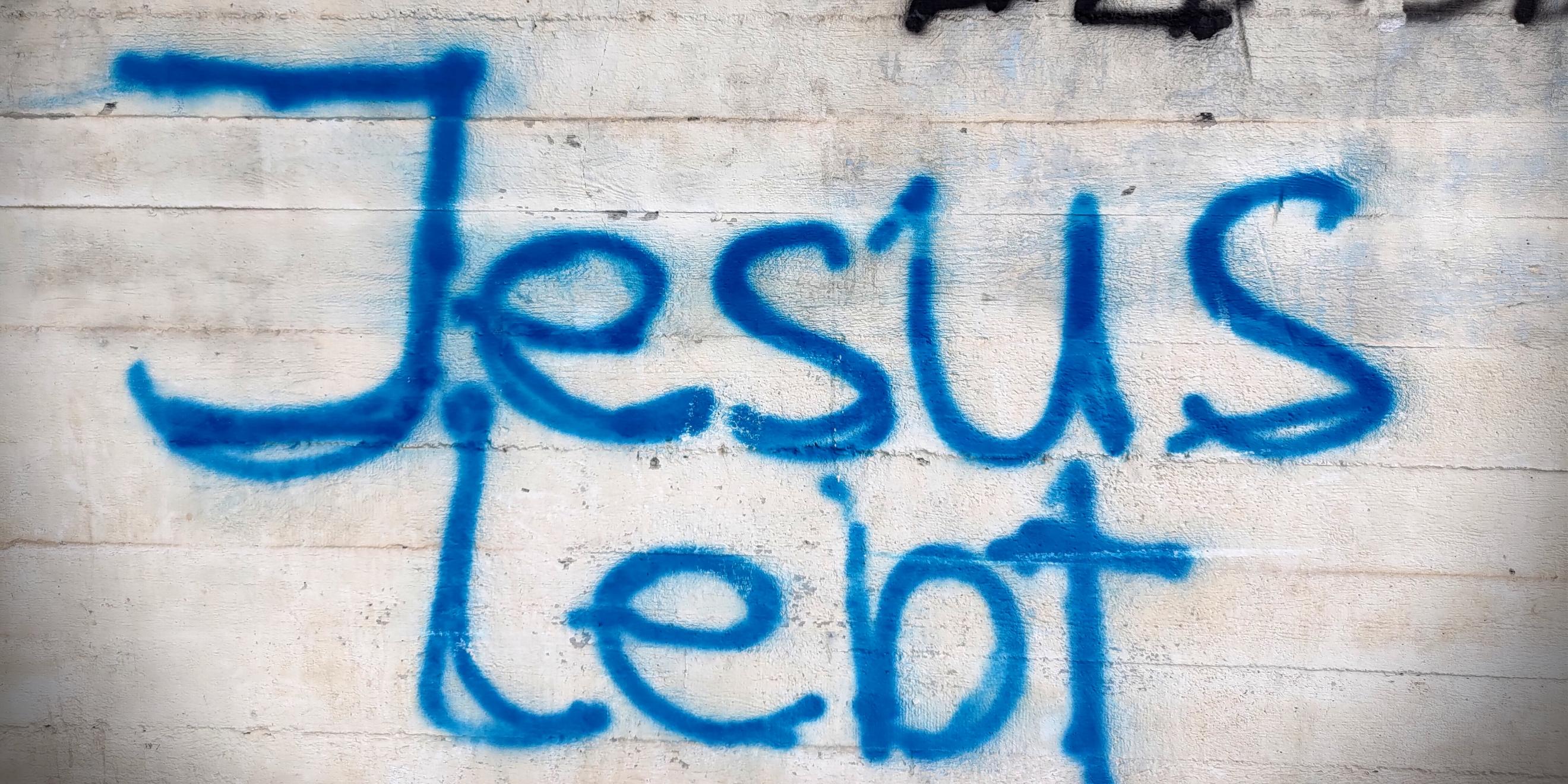 Man sieht ein Graffity an einer Mauer mit der Aufschrift 'Jesus lebt'