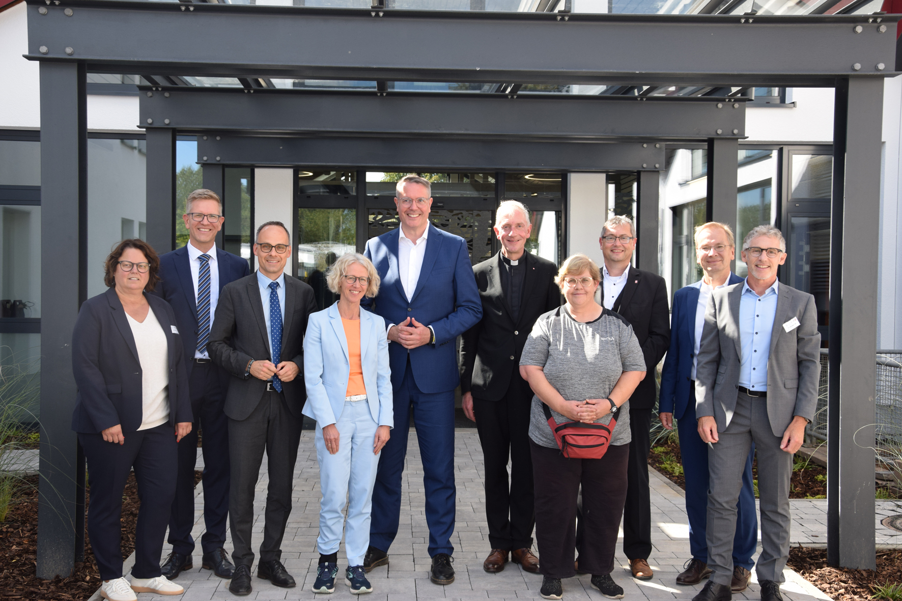 10 Frauen und Männer stehen vor dem Eingang der Caritas Werkstatt Sinzig und lächeln in die Kamera.