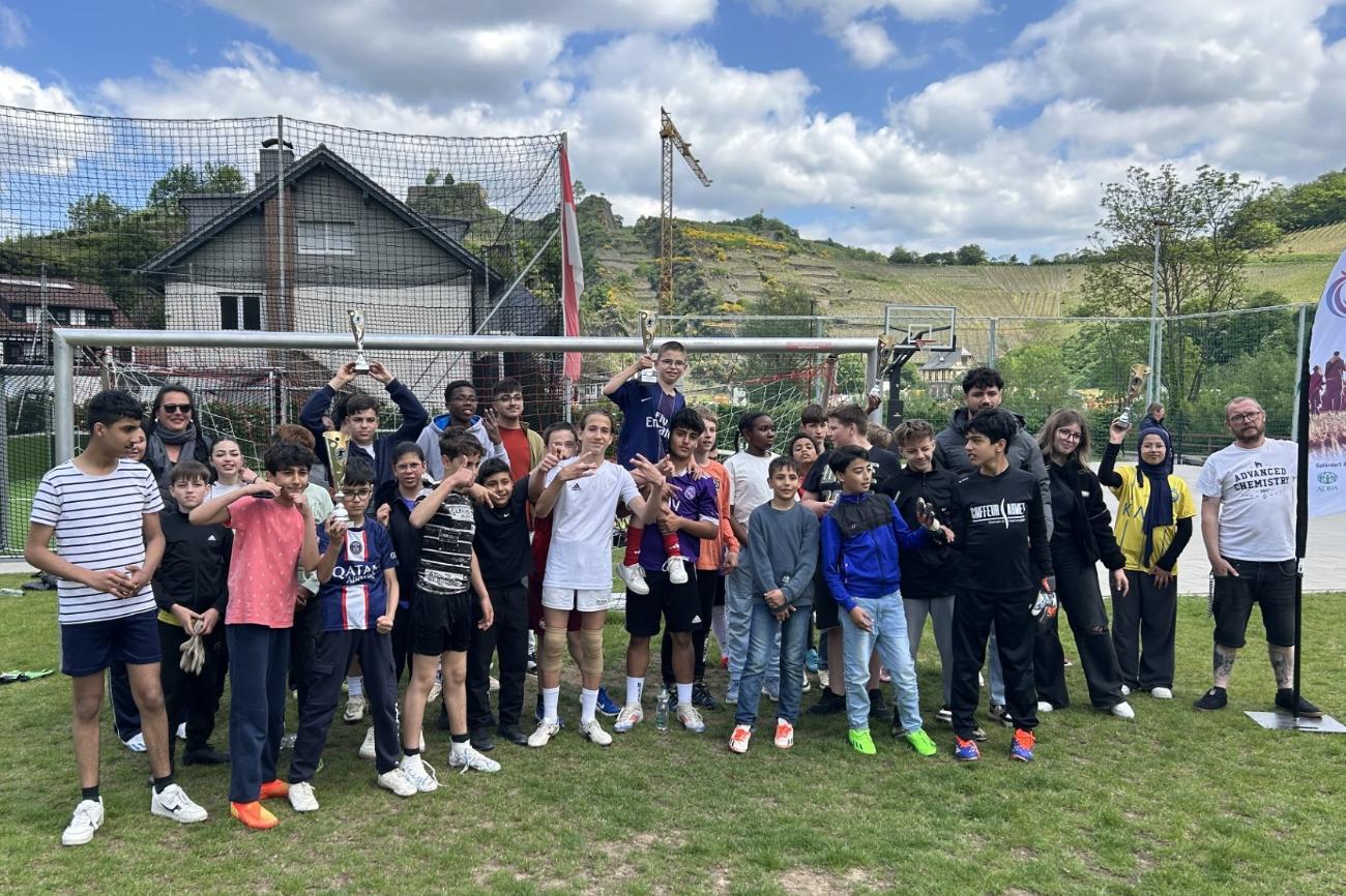 Mitspielerinnen und Mitspieler beim Fußballturnier in Mayschoß (c) Patrick Book EIne Gruppe von Jugendlichen und Erwachsenen steht vor einem Fussballtor.