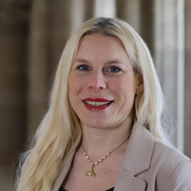 Portraitfoto von Kathrin Schmitt. Eine Frau mittleren Alters mit langen blonden Haaren lächelt in die Kamera.