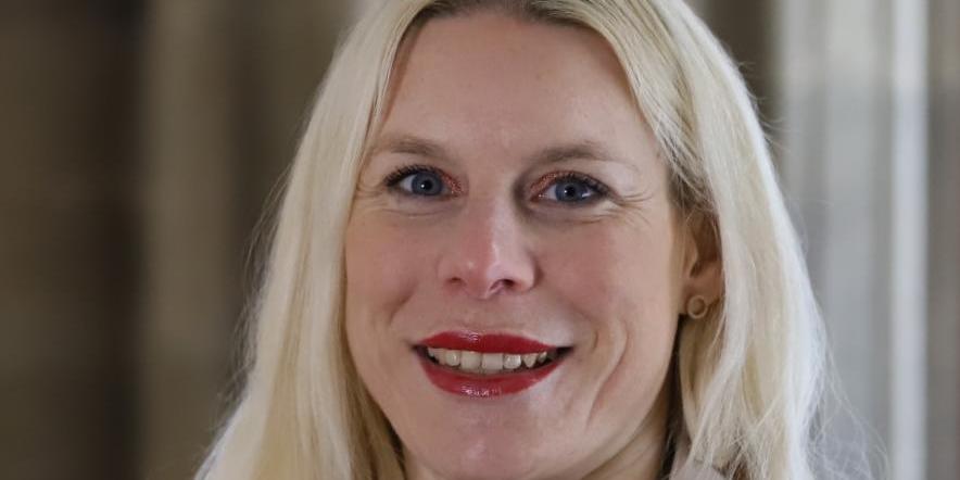 Portraitfoto von Kathrin Schmitt. Eine Frau mittleren Alters mit langen blonden Haaren lächelt in die Kamera.