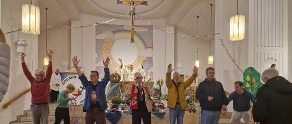 Erntedank im Glas 2025 (c) Patricia Alt Während eines Gottesdienst zu Erntedank in der Kirche, gebärden Menschen vor dem Altar Lieder, indem sie ihre Arme nach oben halten.