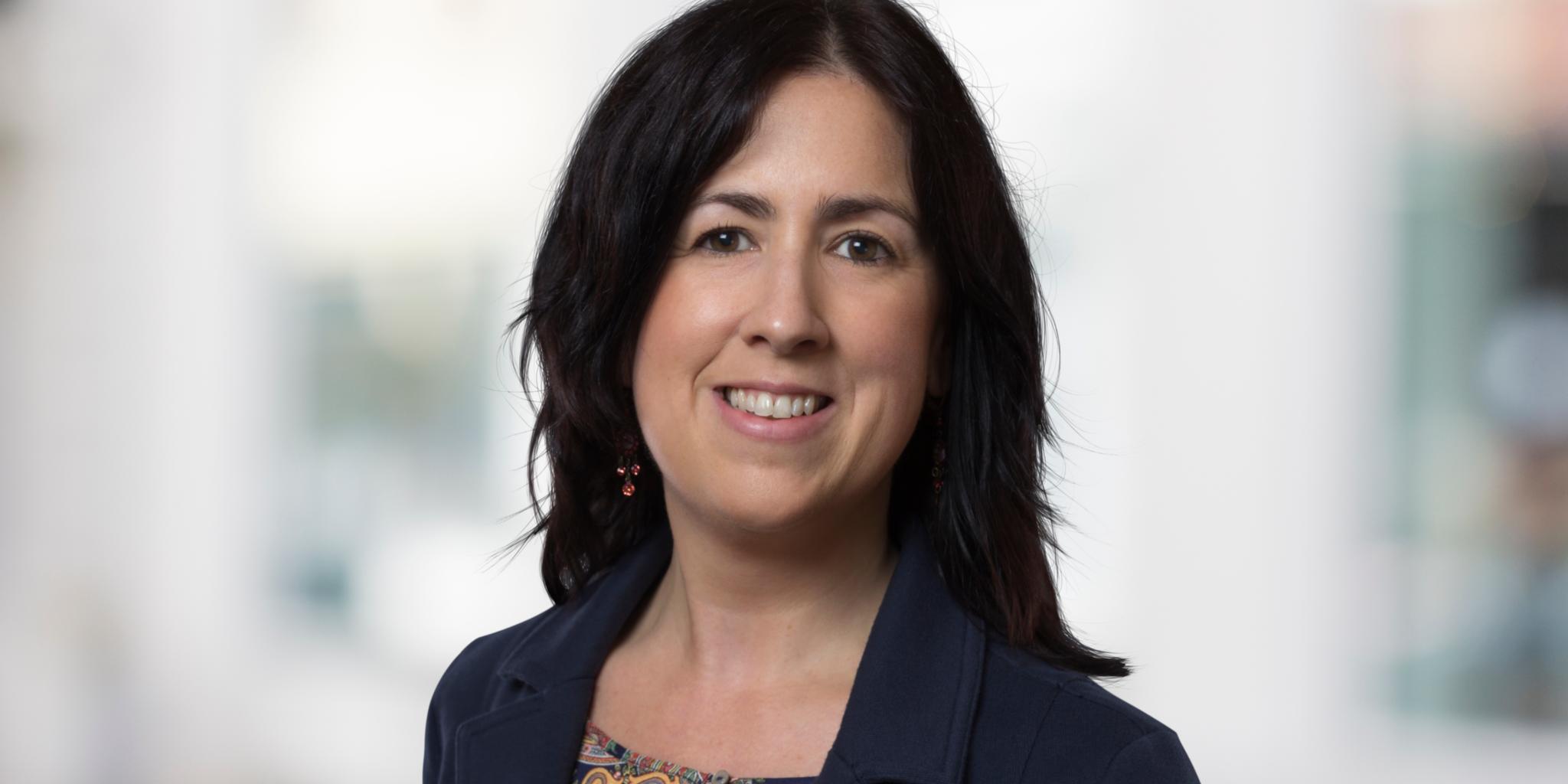 Portraitfoto von Nicole Maxmini. Frau mittleren Alters mit schulterlangen schwarzen Haaren schaut in die Kamera.