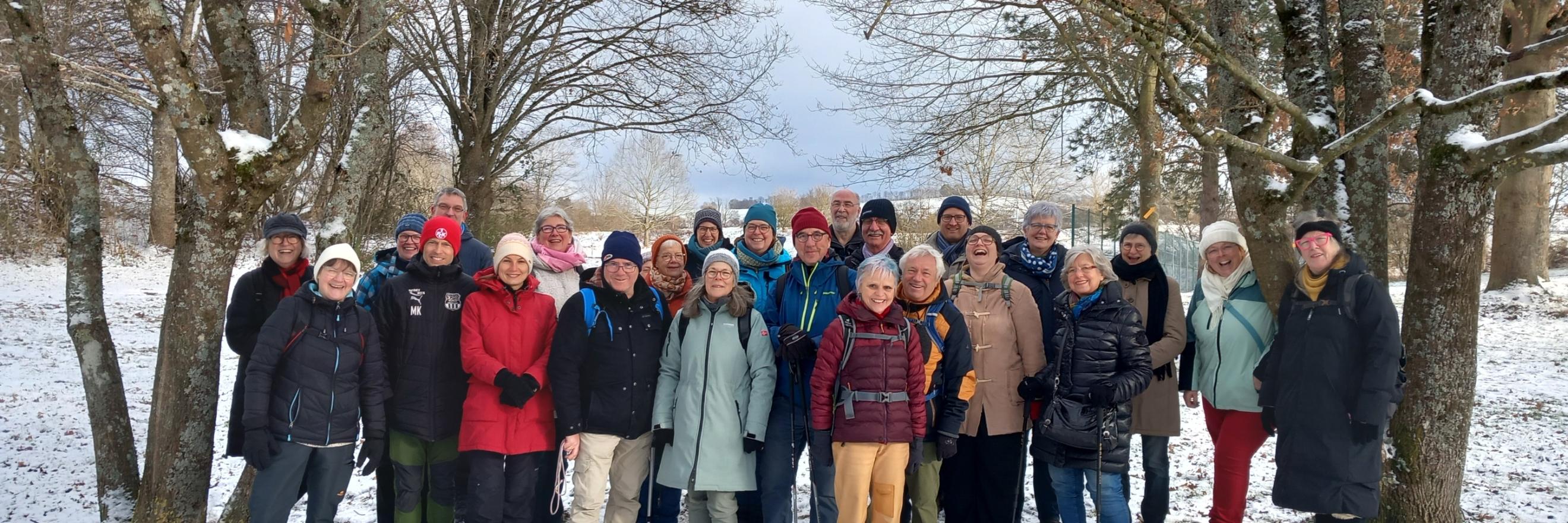 Gruppe der Teilnehmenden des Projektes Hoffnungsschimmer stehen auf einer Wiese im Schnee und lächeln in die Kamera.