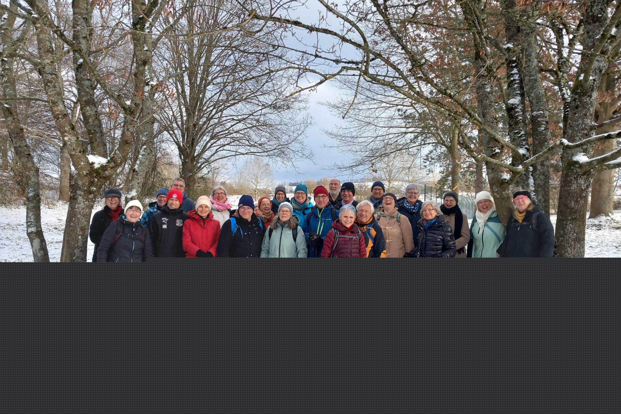 Gruppe der Teilnehmenden des Projektes Hoffnungsschimmer stehen auf einer Wiese im Schnee und lächeln in die Kamera.
