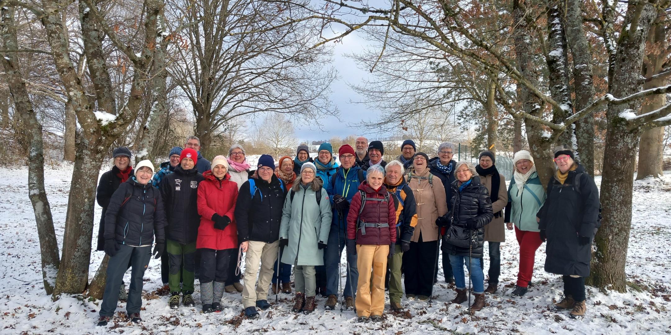 Gruppe der Teilnehmenden des Projektes Hoffnungsschimmer stehen auf einer Wiese im Schnee und lächeln in die Kamera.