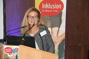 Das BIld zeigt Prof. Dr. Elisabeth Wacker bei einem Vortrag zu der Fachtagung des Arbeitsfeld Inklusion 2017. Die Frau mittleren Alters mit Brille und blonden Haaren steht am Rednerpult und spricht in zwei Mikrofone.