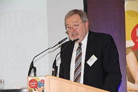 Das BIld zeigt Prof. Dr. Ulrich Heimlichr bei einem Vortrag zu der Fachtagung des Arbeitsfeld Inklusion 2017. Der ältere Mann mit Brille, schwarzem Anzug und Krawatte steht am Rednerpult und spricht in zwei Mikrofone.