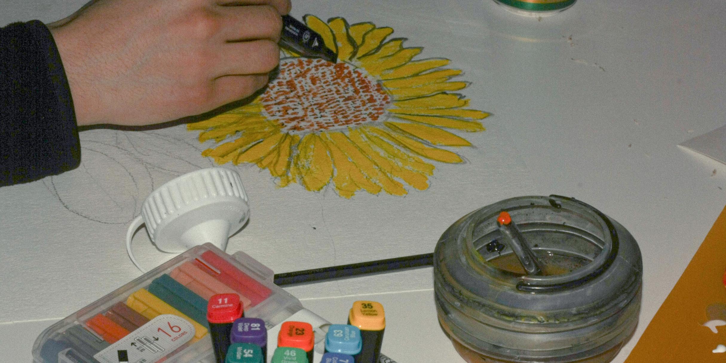 Person malt eine Sonnenblume