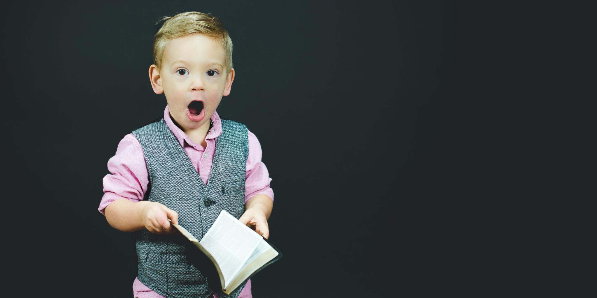 Man sieht einen kleinen Jungen, der ein Liederbuch in der Hand und den Mund zum Singen geöffnet hat