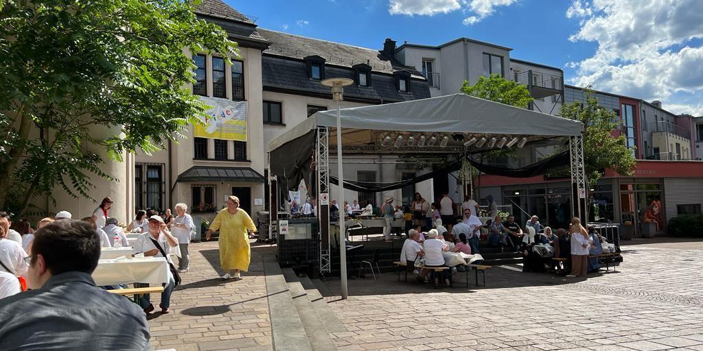 Menschen sitzen gemeinsam an Tischen beim interreligiösem Friedensmahl 2022