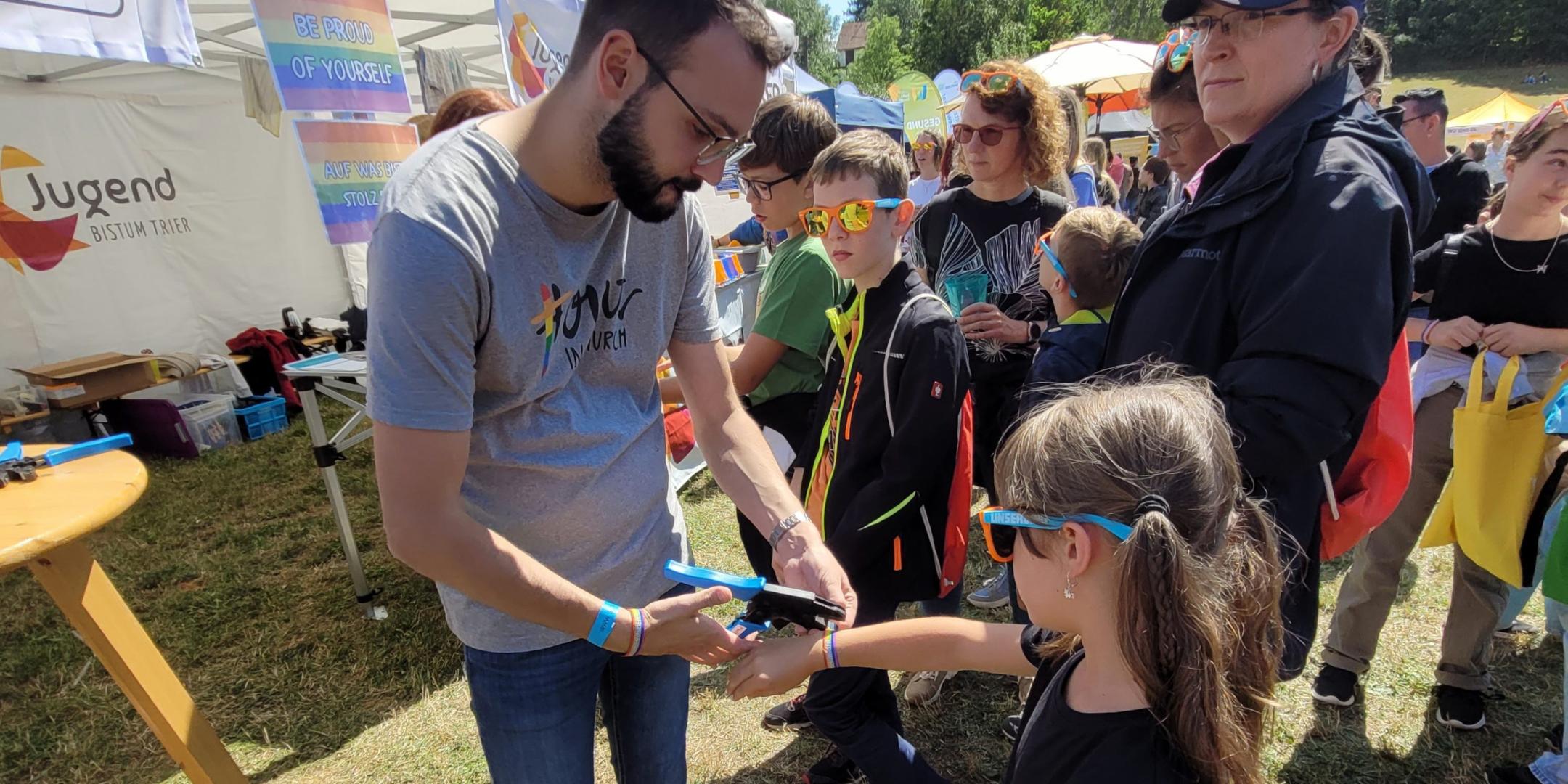 Die siebenjährige Lia, die mit ihrer Mutter vor Ort war, ließ sich stolz von Gemeindereferent Andreas Diegler ein regenbogenfarbenes Festivalbändchen umlegen.