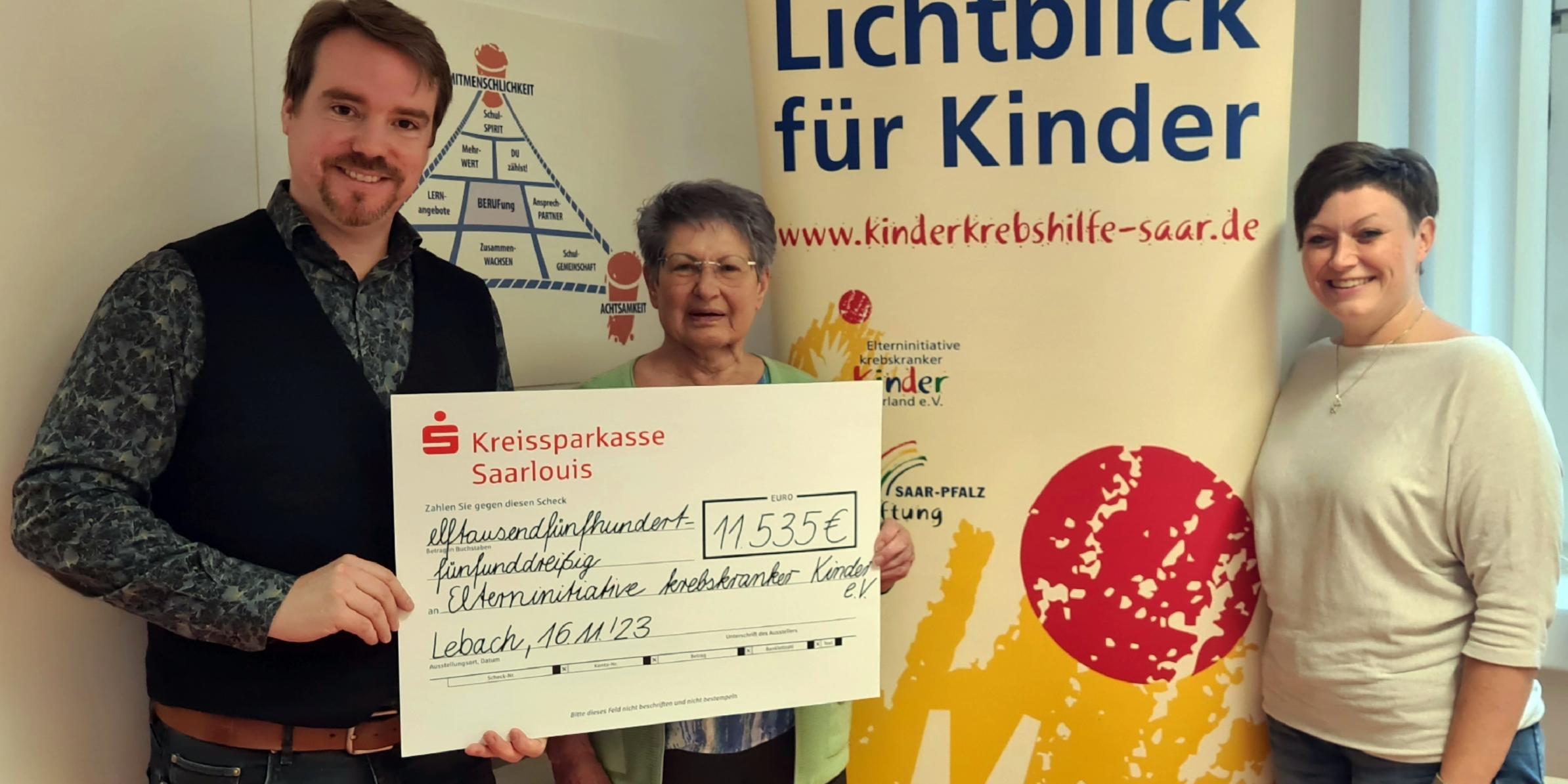 Die Schulleiter Andreas Hackert und Verena Laase überreichen den Spendenscheck an eine Vertreterin der Elterninitiative krebskranker Kinder e.V.