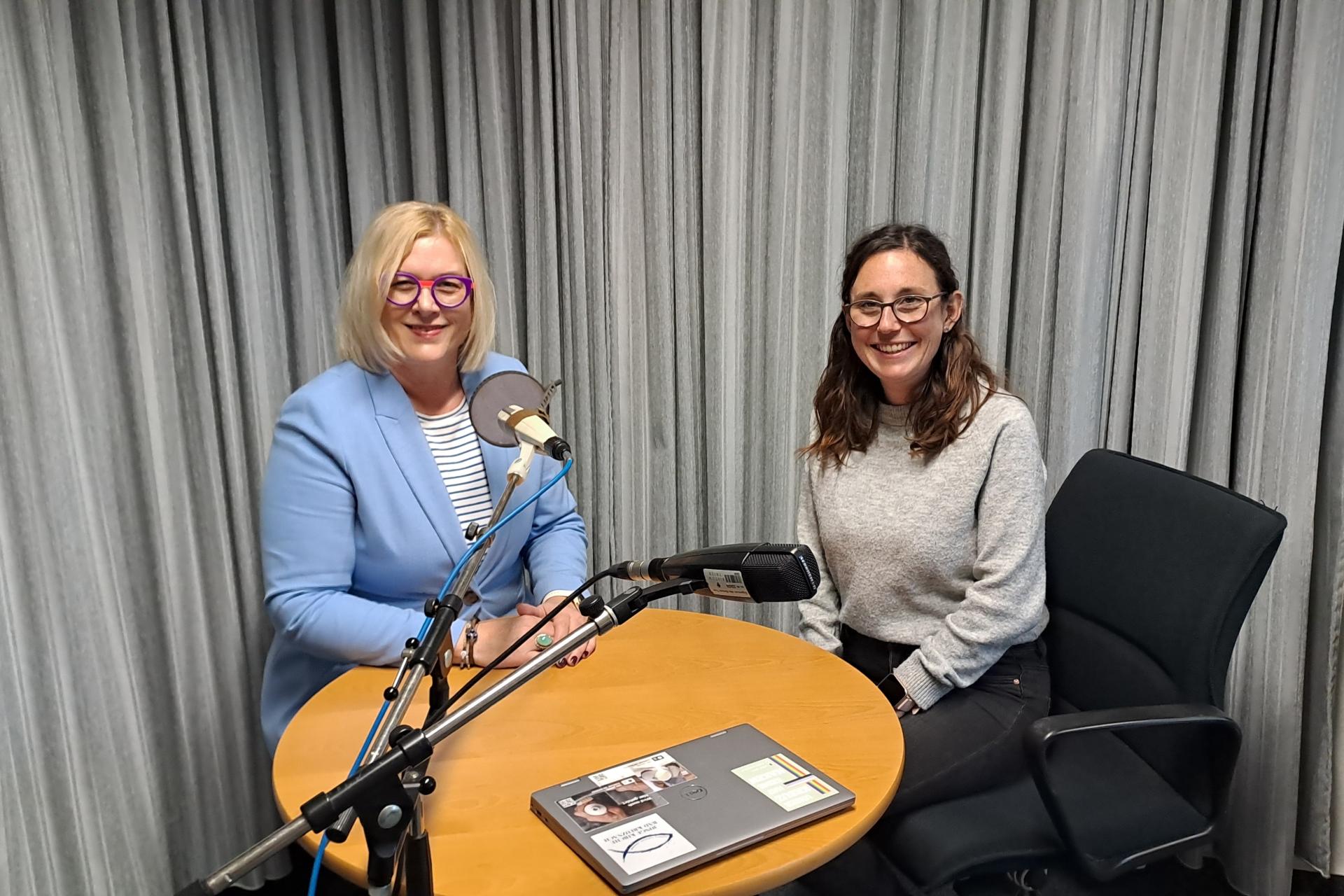 Auf dem Foto sitzen Andrea Wolter vom SkF (links) und Luisa Maurer (rechts) im Aufnahmestudio an einem Tisch und schauen in die Kamera.