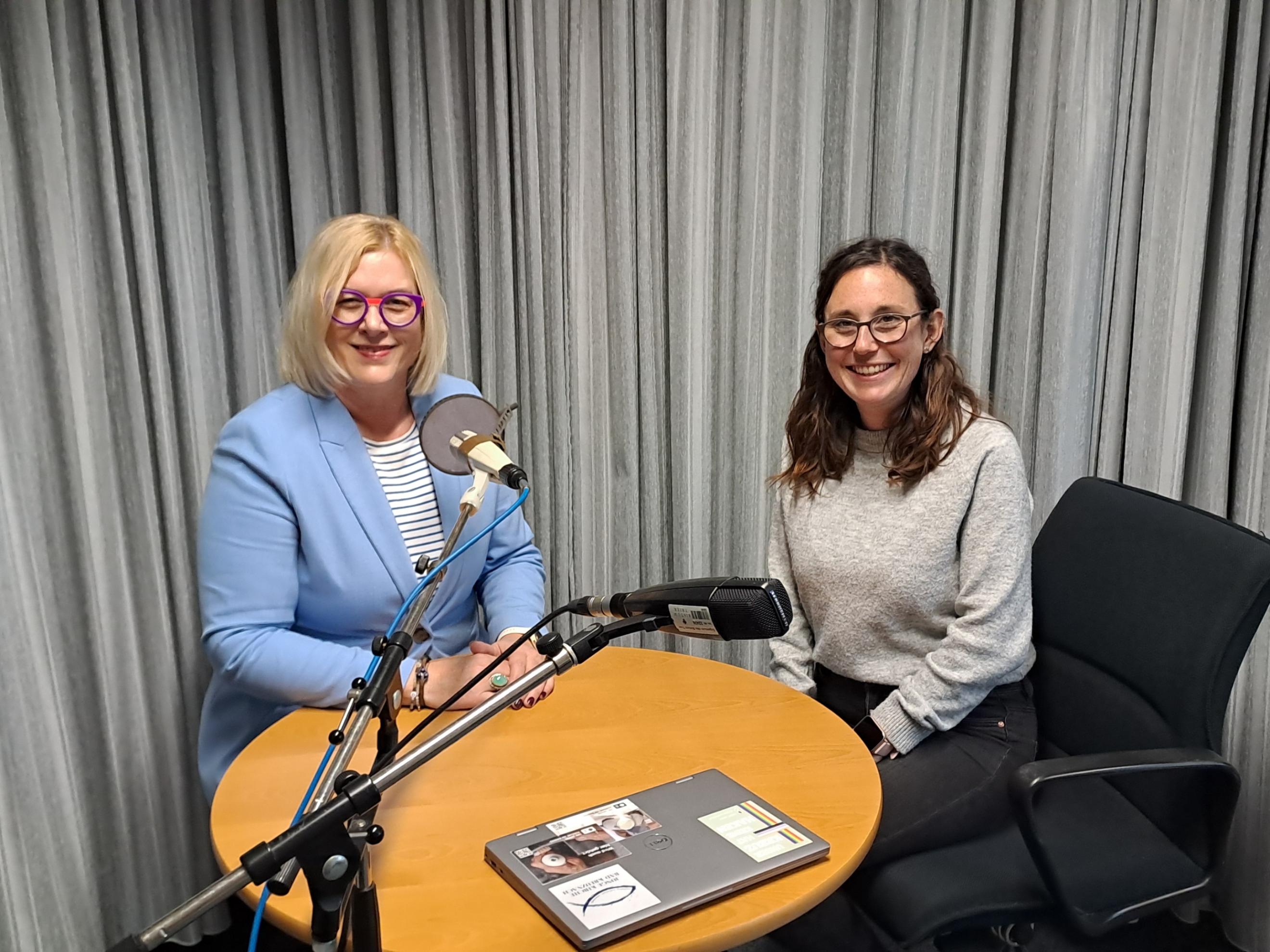 Auf dem Foto sitzen Andrea Wolter vom SkF (links) und Luisa Maurer (rechts) im Aufnahmestudio an einem Tisch und schauen in die Kamera.