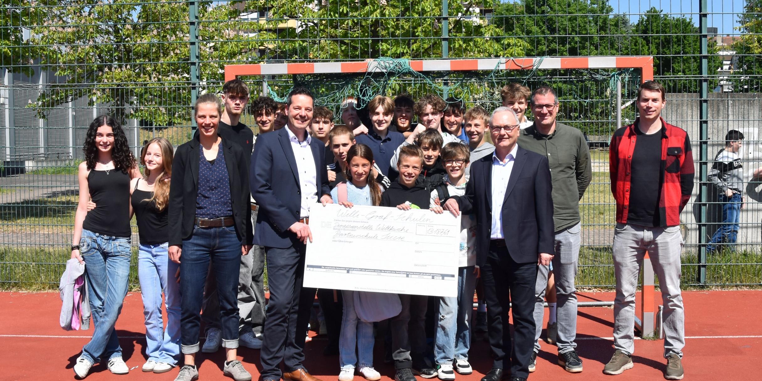 Schülerinnen und Schüler der Willi-Graf-Schulen und ihre Schulleiter Stefan Kilz und Stephan Arnold überreichen einen Scheck über 13.000 Euro an Thorsten Hoffmann und Katharina Nilles von der Diözesanstelle Weltkirche.