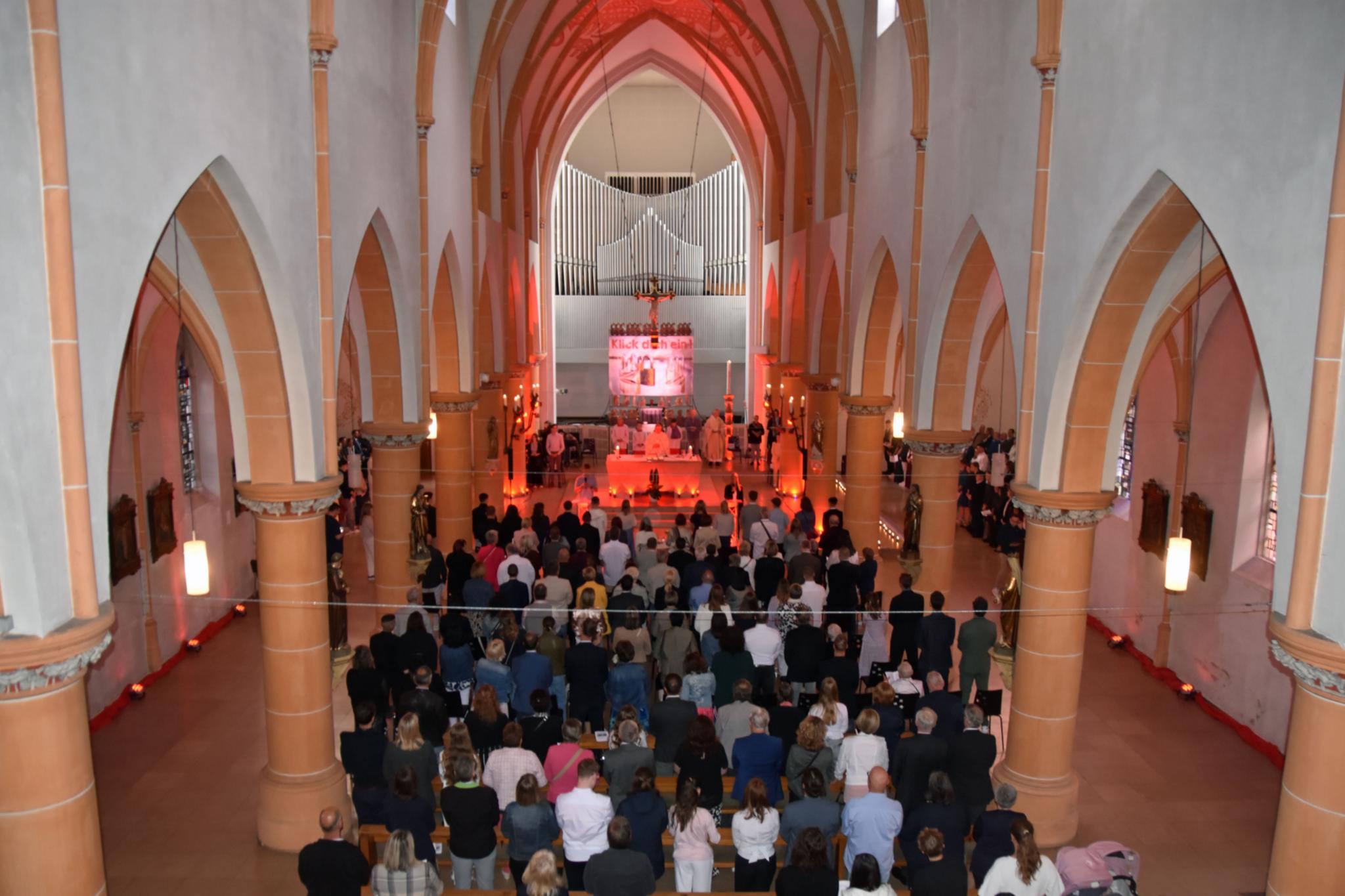 Man blickt von oben auf die vollbesetzten Sitzbänke einer Kirche