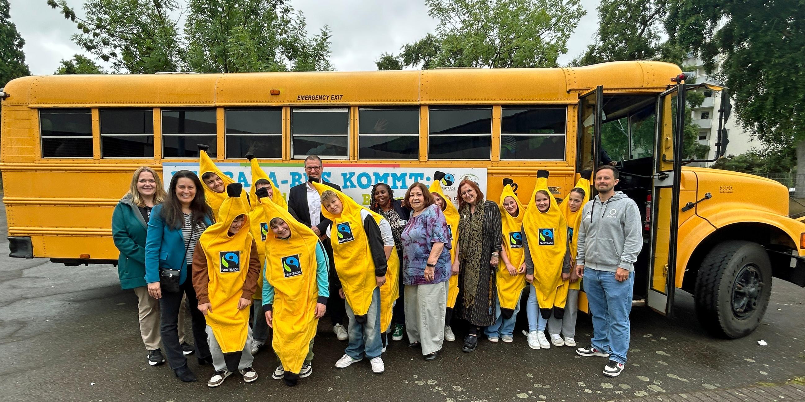 Vor dem Banabus feiern Schülerinnen und Schüler gemeinsam mit Schulleiter Stephan Arnold, Regionalverbandsdirektorin Carolin Lehberger, Bildungsdezernentin Kerstin Theobald und Winnie Mbindyo von Fairtrade Deutschland das zehnte Jubiläum der Willi-Graf-Realschule als Fairtrade-School.