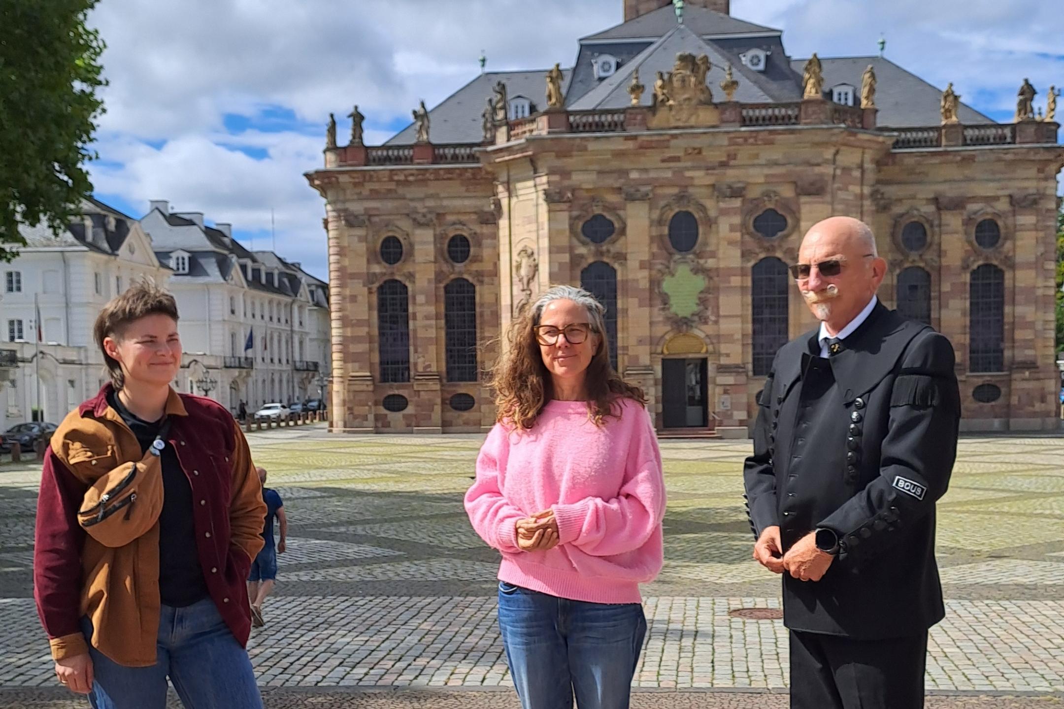 Drei Personen stehen vor einer Kirche.