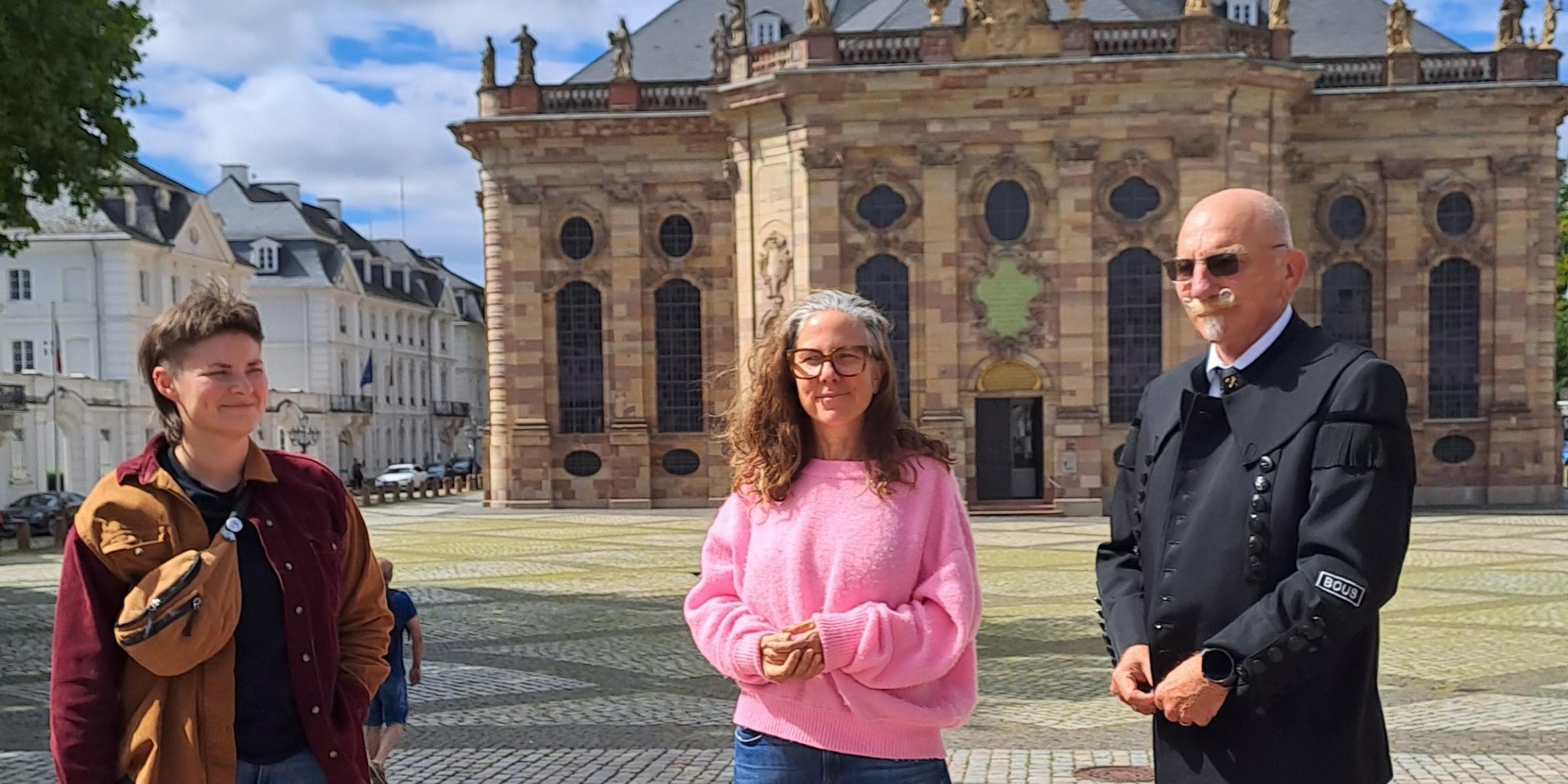 Drei Personen stehen vor einer Kirche.