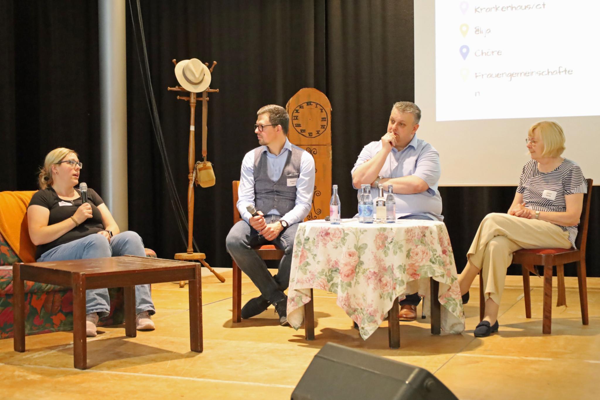 Sonja Schäfer (Caritas GWA Burbach, links), Schulleiter Christian Dahlke (Zweiter von rechts) und Ursula Spang (kfd, Caritas, rechts) berichten Moderator Dominik Holl (Zweiter von links) über Vernetzungen innerhalb ihrer kirchlichen Gruppen.