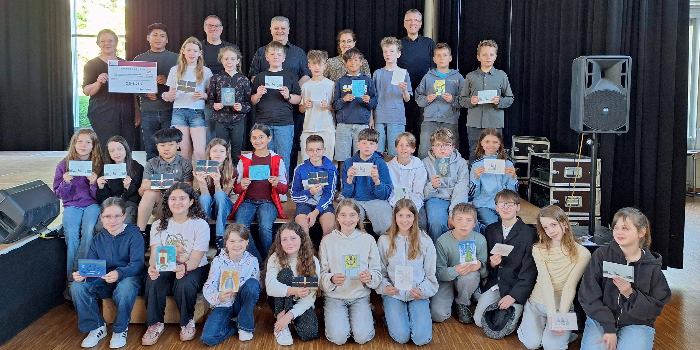 Annemarie Reimers (Leiterin Didaktik am Willi-Graf Gymnasium), Kevin Daniel Vallejos (Freiwilliger), Stephan Arnold (Schulleiter der Willi-Graf-Realschule), Christian Dahlke (Schulleiter des Willi-Graf-Gymnasiums), Evelyn Zimmer (Abteilung Jugend) und Bernd Schütz (Schulpfarrer) gemeinsam mit Schülerinnen und Schülern der Willi-Graf-Schulen bei der Spendenübergabe.