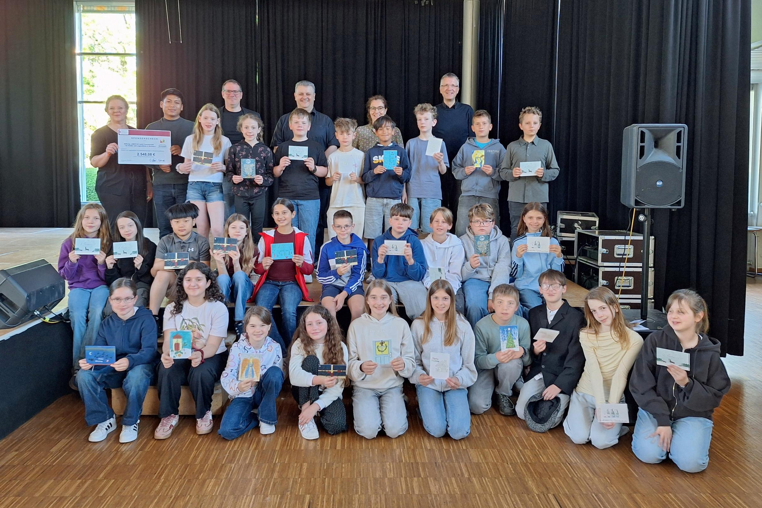 Annemarie Reimers (Leiterin Didaktik am Willi-Graf Gymnasium), Kevin Daniel Vallejos (Freiwilliger), Stephan Arnold (Schulleiter der Willi-Graf-Realschule), Christian Dahlke (Schulleiter des Willi-Graf-Gymnasiums), Evelyn Zimmer (Abteilung Jugend) und Bernd Schütz (Schulpfarrer) gemeinsam mit Schülerinnen und Schülern der Willi-Graf-Schulen bei der Spendenübergabe.
