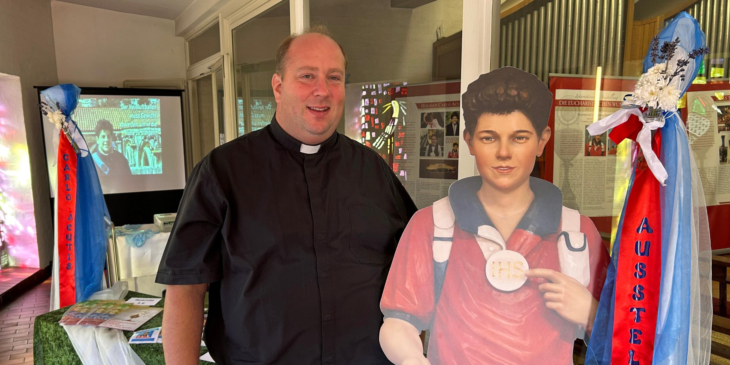 Pfarrer Lars Meiser mit einem lebensgroßen Aufsteller des Heiligen Carlo Acutis im Eingangsbereich der Klosterkirche.