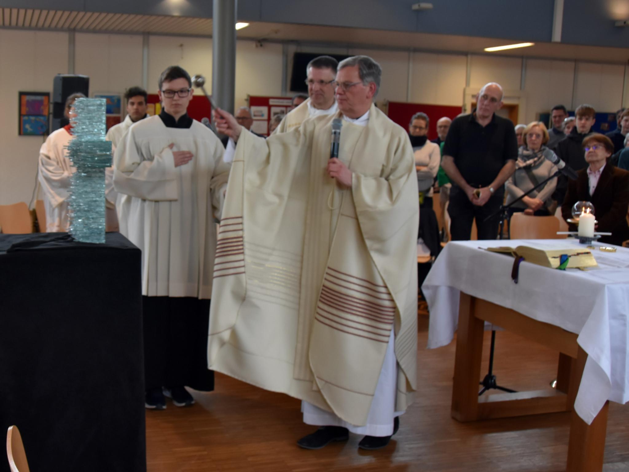 Generalvikar Ulrich Graf von Plettenberg segnet das von Schülern gestaltete Kreuz aus Glas.