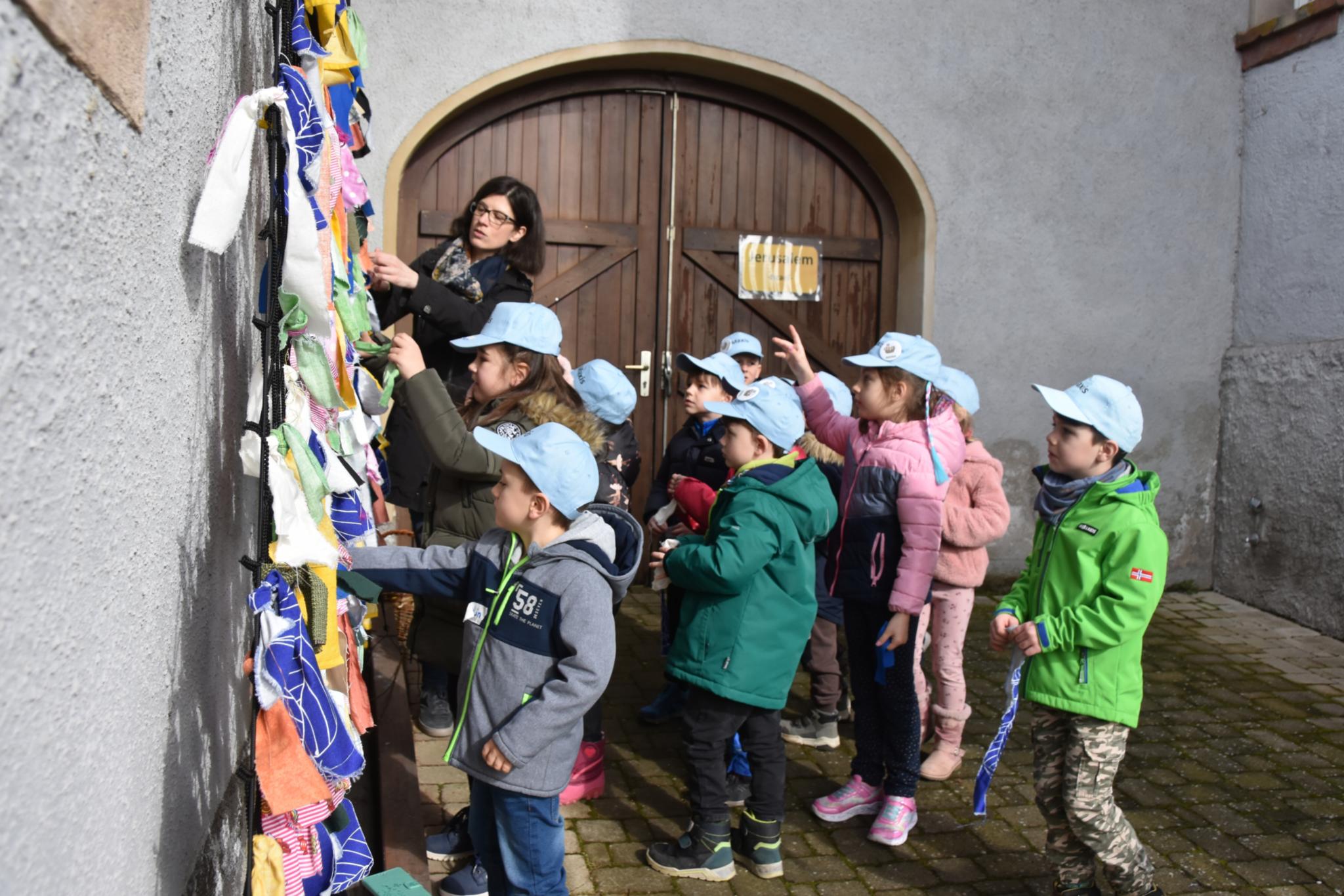Am Stadttor von Jerusalem knüpfen die Kinder symbolisch Stoff in ein Netz.