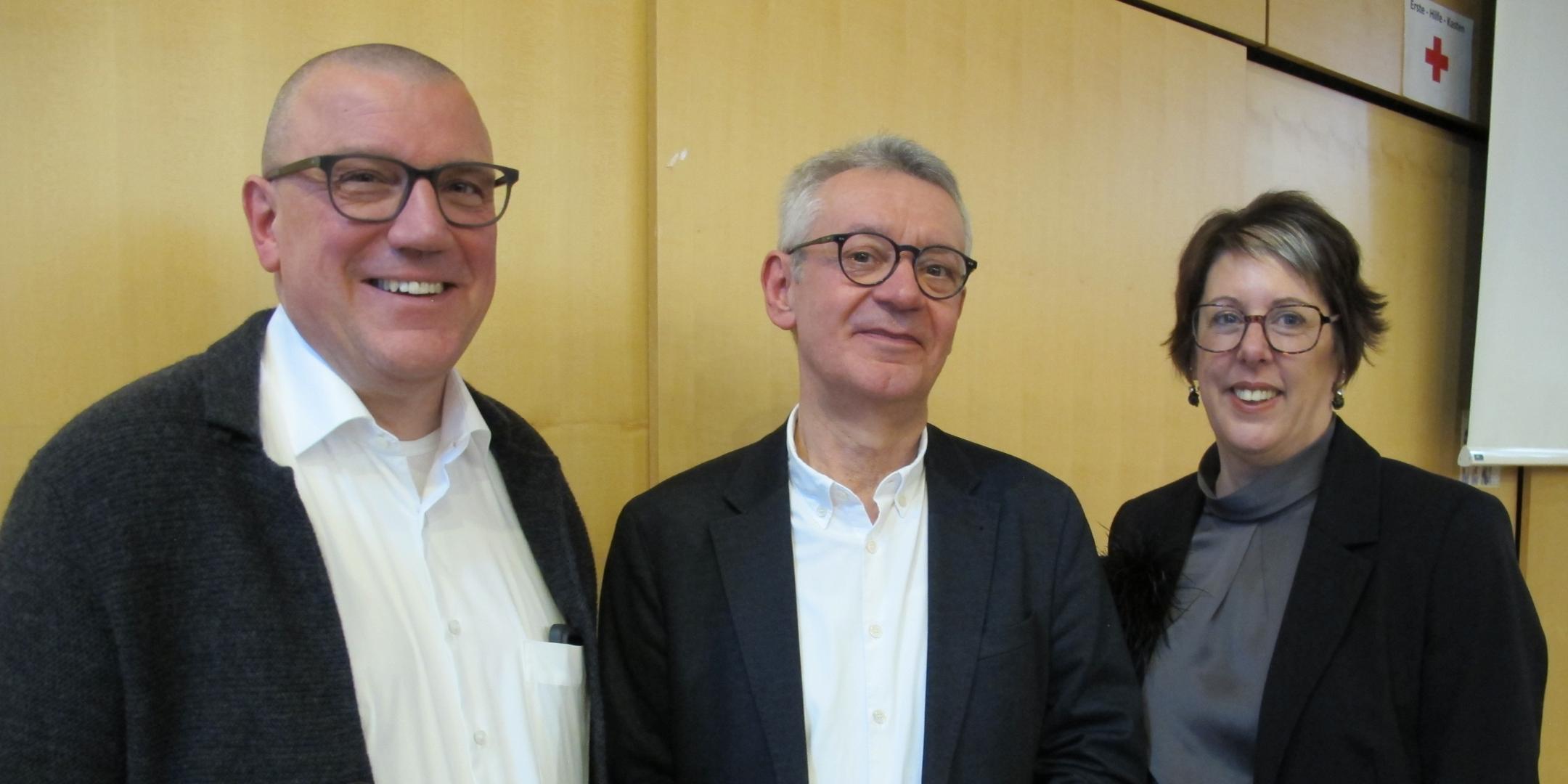 Zwei Männer und eine Frau stehen für ein Gruppenbild zusammen.