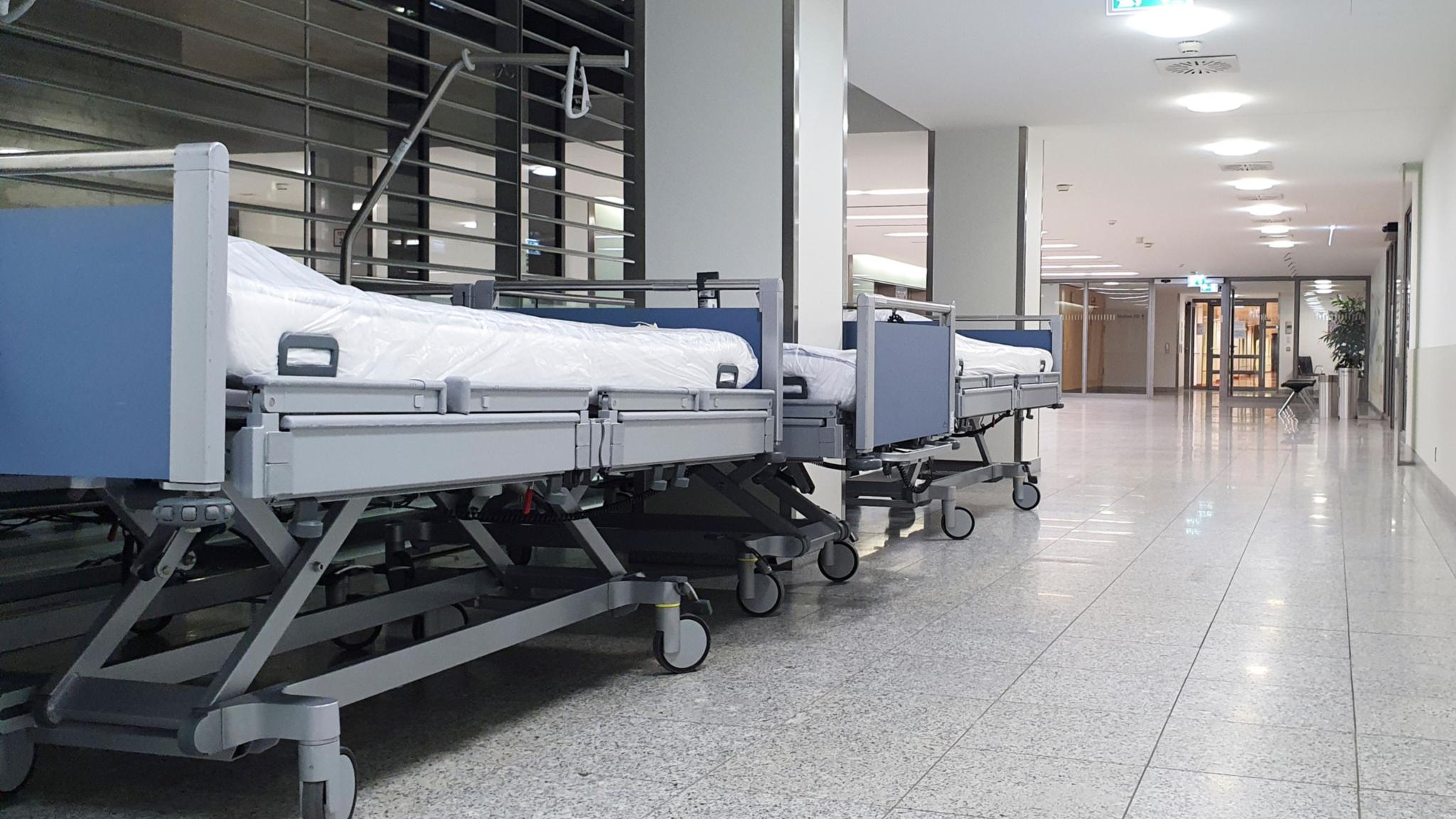 Es sind leere Krankenhausbetten zu sehen, die auf dem Flur stehen.