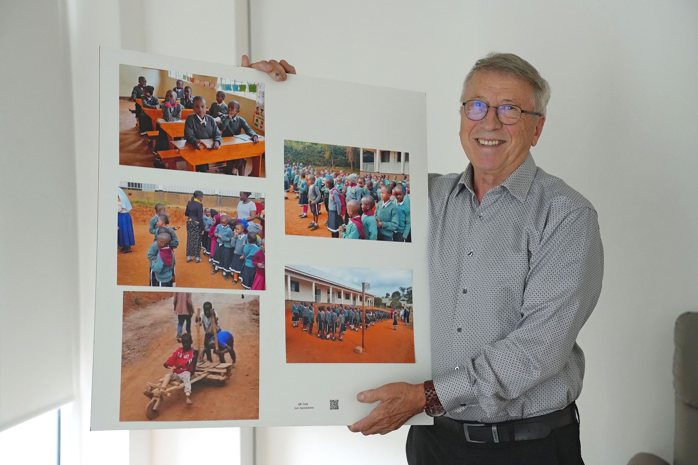 Eduard Kimmlingen zeigt ein Plakat mit Fotos der Projekte in Tansania.
