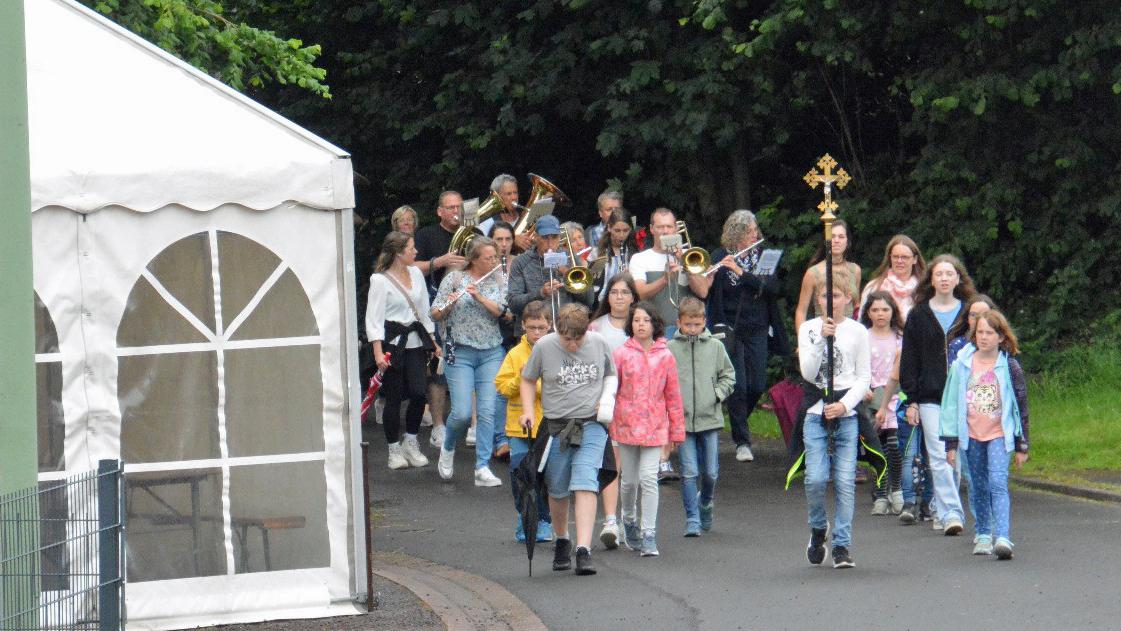 Eine Gruppe von Kindern wandert, vornweg trägt ein Kind ein Kreuz