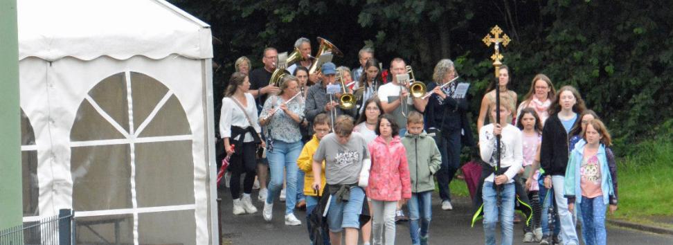 Eine Gruppe von Kindern wandert, vornweg trägt ein Kind ein Kreuz