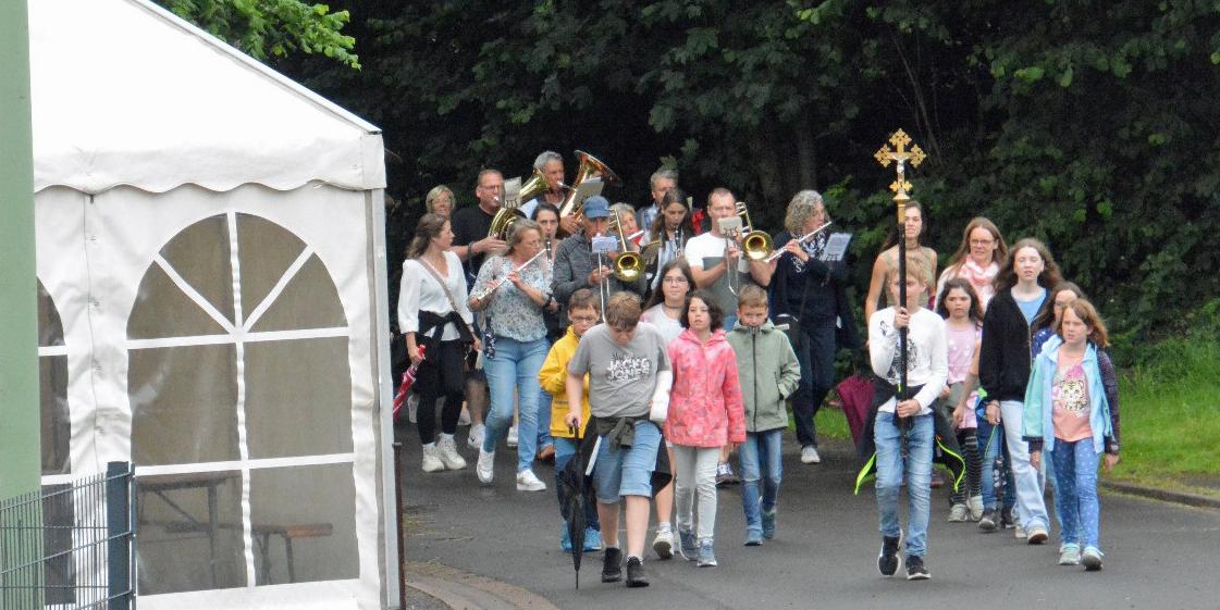 Eine Gruppe von Kindern wandert, vornweg trägt ein Kind ein Kreuz