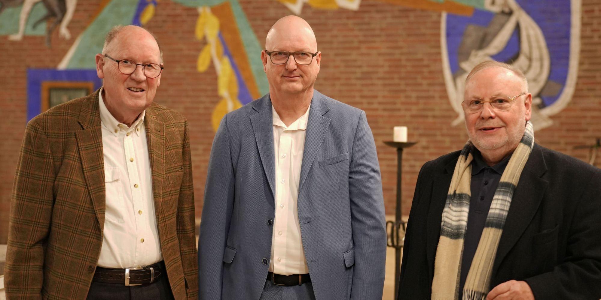 Drei Männer blicken lächelnd in die Kamera