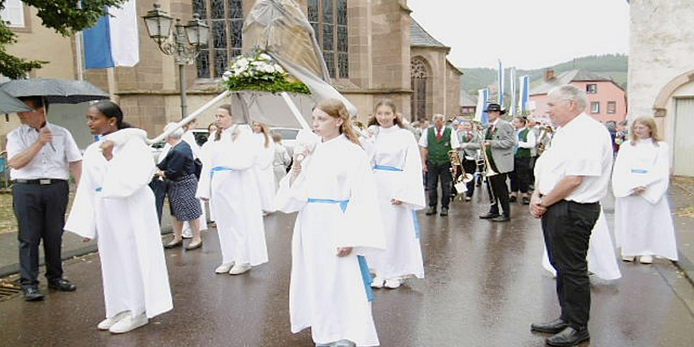 Weiß gekleidete Mädchen tragen eine Marienfigur